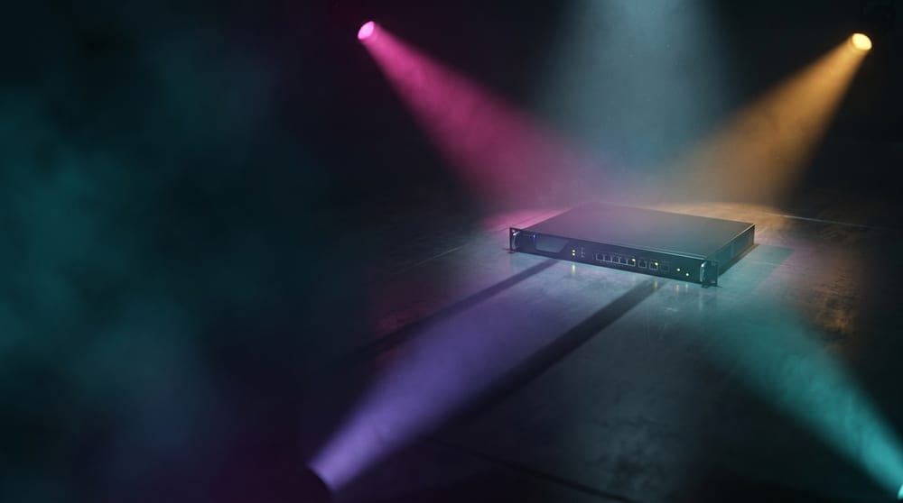 A single mitigation appliance lit by four coloured beams reaching it from four directions outside the frame.